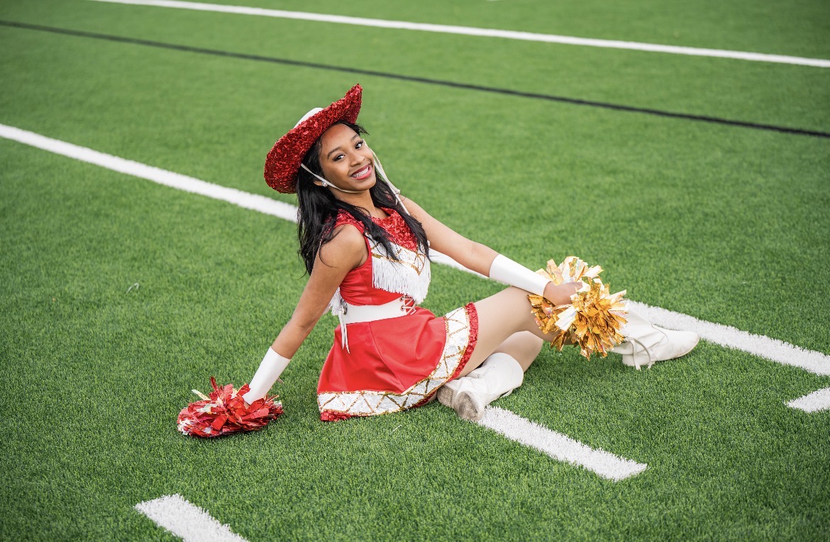 Jewel posing on the football field with red and gold poms