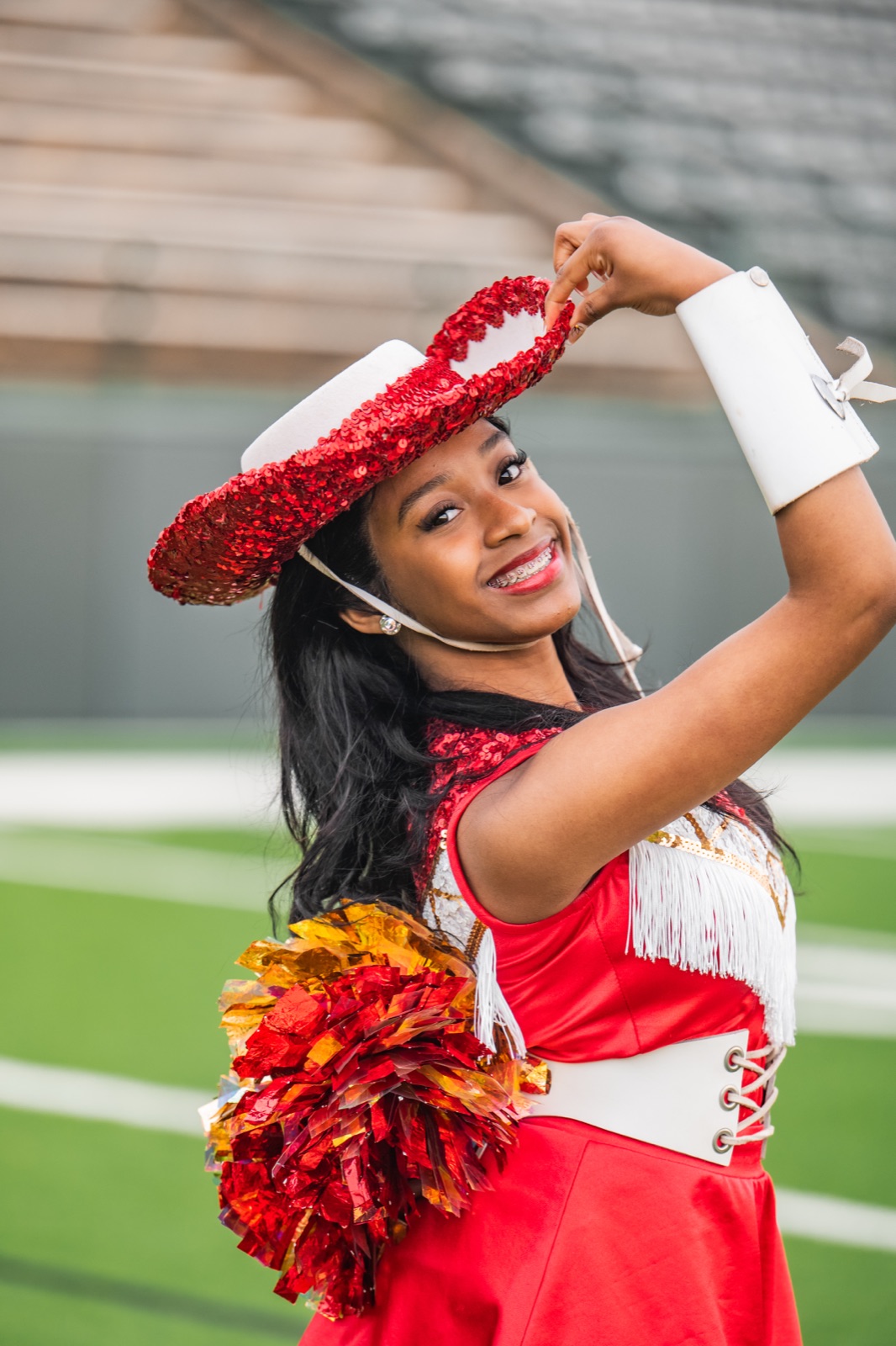 Jewel tipping her red sequin performance hat on the field