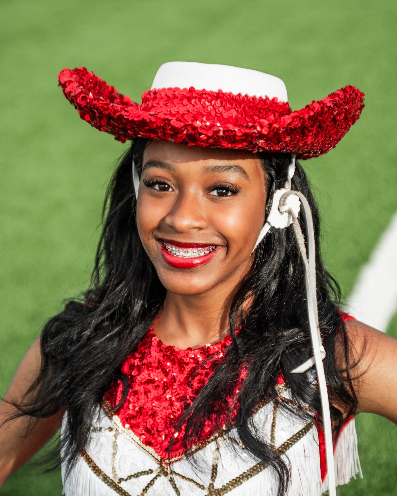 Jewel Monet smiling in her red sequin performance hat